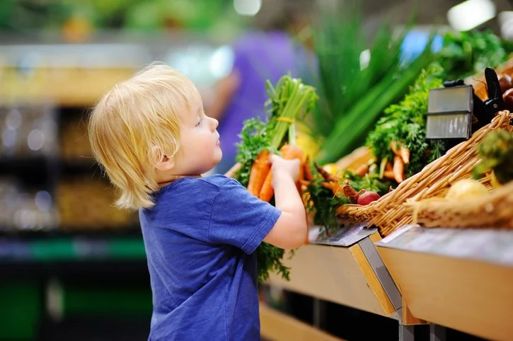 Toddler reaching for fresh produce while grocery shopping