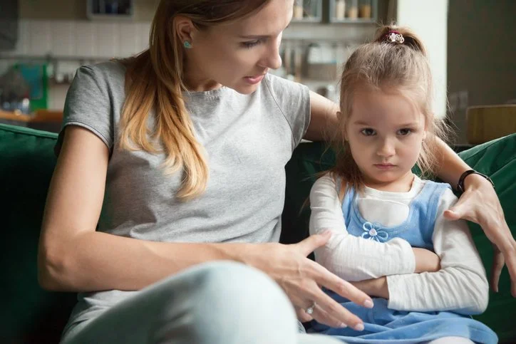 Parent talking closely with a child sitting on the couch