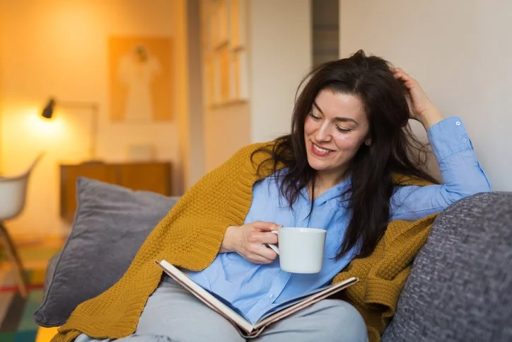 Parent relaxing with a warm drink and a book at home