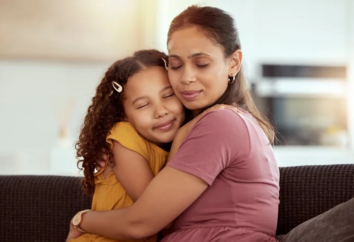 Parent and child sharing a gentle hug on the couch