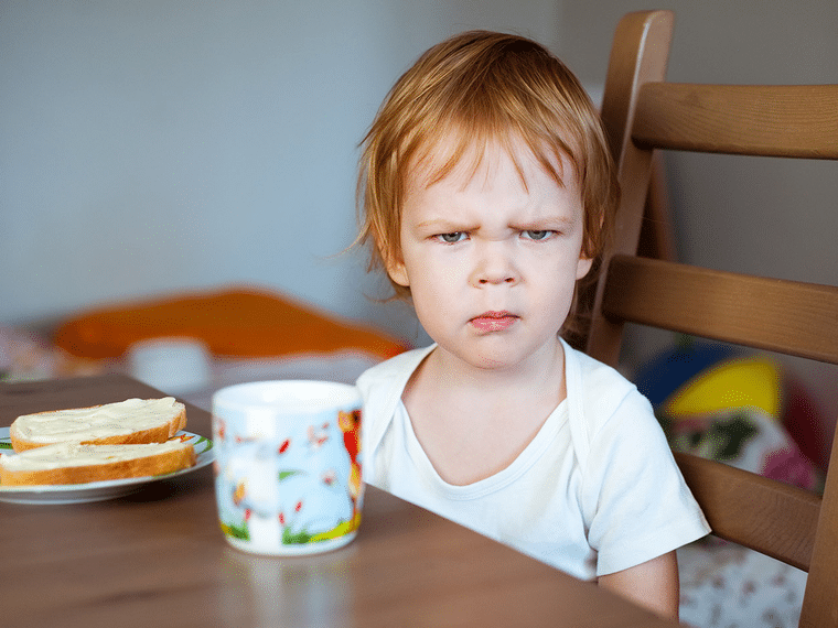 Young child with a frustrated expression sitting at the table