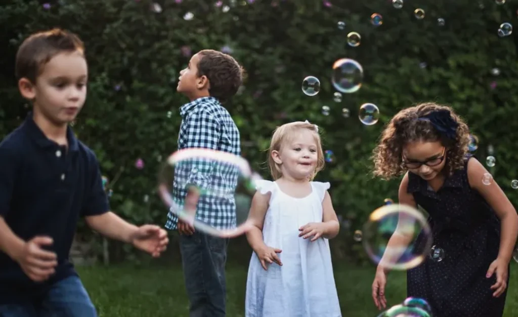 Children playing outdoors together, chasing bubbles in the yard