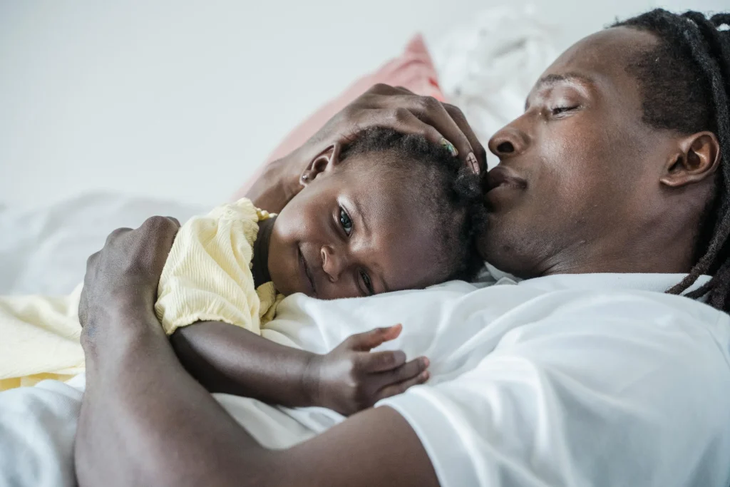 Father lying in bed while cuddling closely with his baby