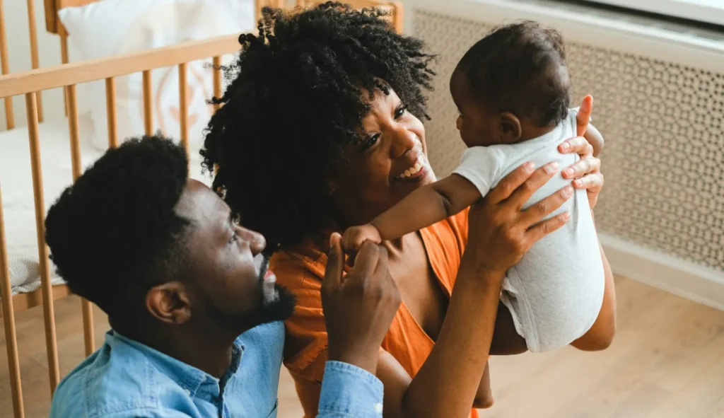 Two parents joyfully bonding with their baby at home