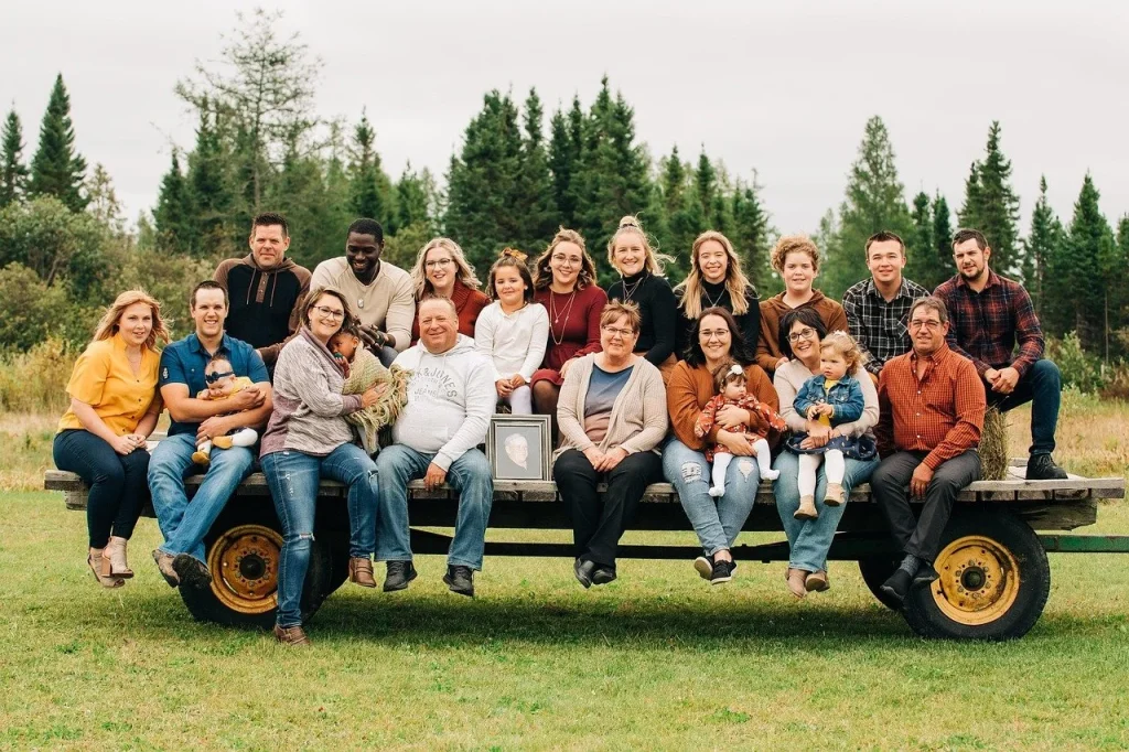 Large extended family posing together outdoors on a hay wagon