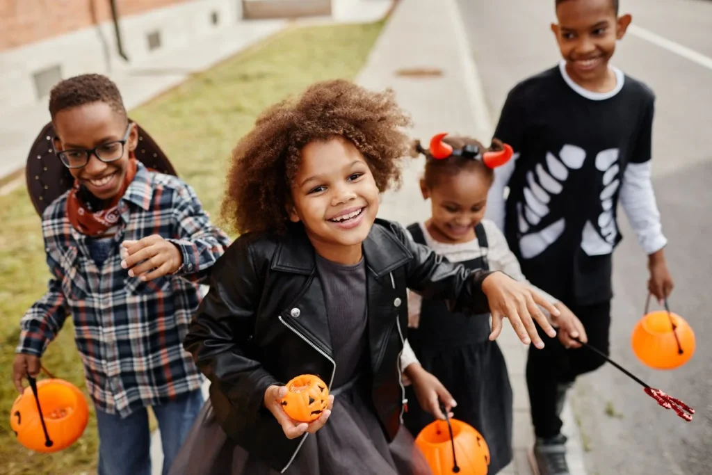 Children in Halloween costumes trick-or-treating with pumpkin buckets