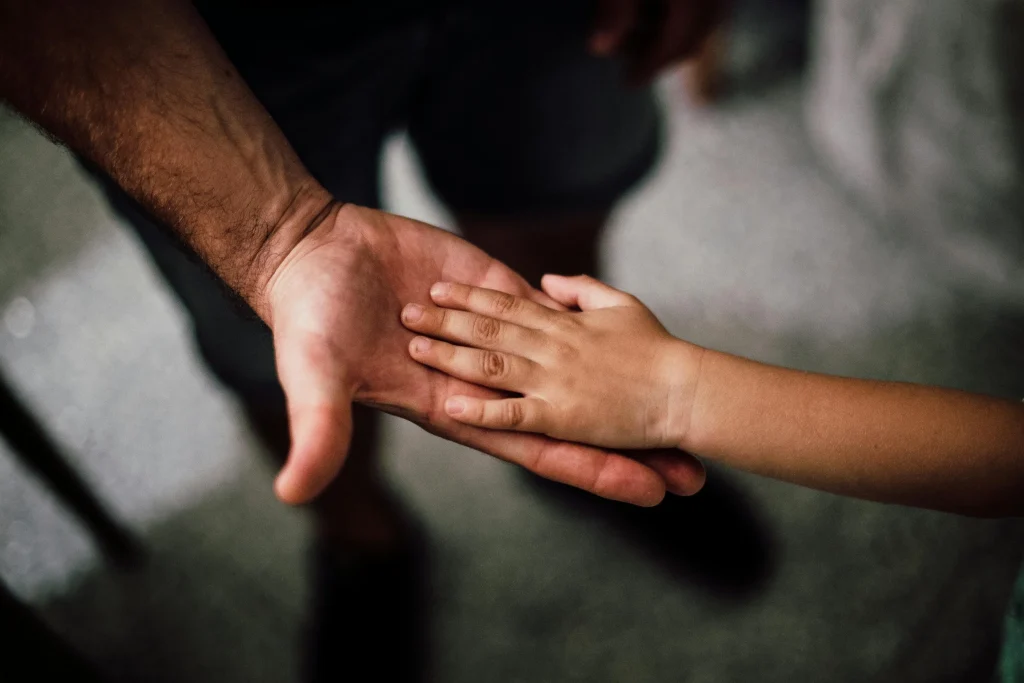 Adult and child's hands touching, symbolizing trust and protection