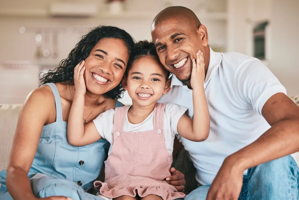 Two smiling parents with their daughter posing together indoors