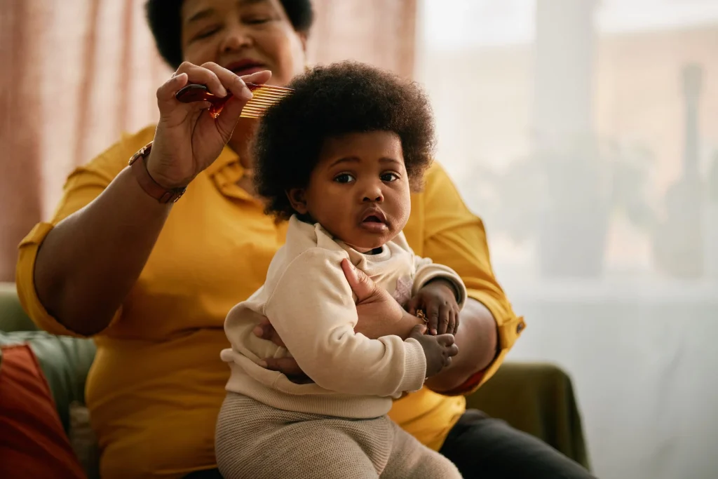 Woman carefully styling a baby's curly hair at home