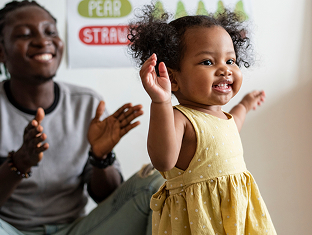 Toddler dancing joyfully in a classroom decorated with fruit artwork