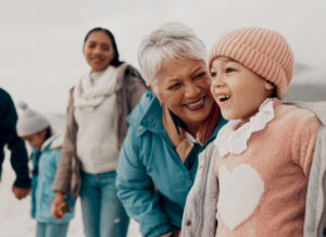 Grandparent laughing joyfully with a young child while family walks nearby outdoors