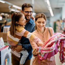 Family of three browsing children's clothing together in a store